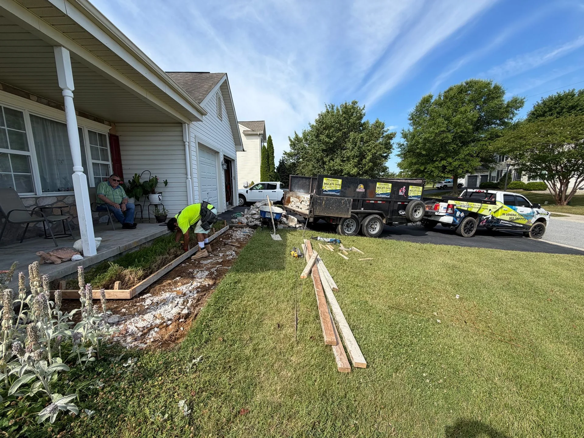 Crew preparing a concrete walkway beside a house